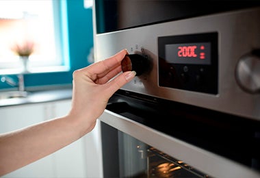 Mujer ajustado temperatura en horno para hacer galletitas fáciles 