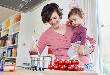 Mujer cocinando con una olla de acero inoxidable junto a su hija