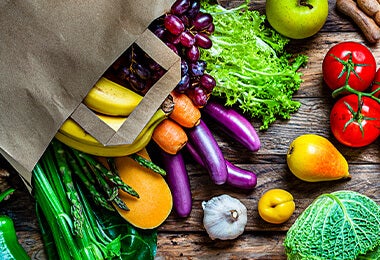   Una mesa con varias frutas y verduras. En el medio hay unas berenjenas alargadas  