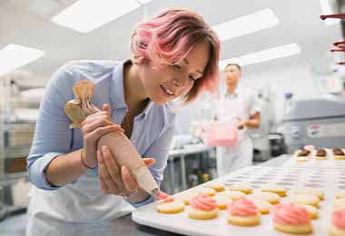   Una mujer usando una manga pastelera, un utensilio de repostería. .    