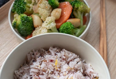 Bowl de arroz acompañado de ensalada de coliflor, brócoli y zanahoria.