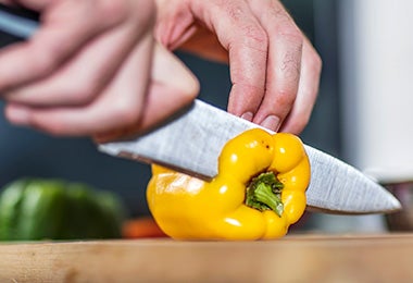  Un morrón amarillo siendo cortado con un cuchillo.