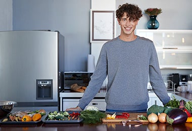 Hombre en cocina con diferentes alimentos, quitar mal olor de la heladera Hombre en cocina con diferentes alimentos, quitar mal olor de la heladera