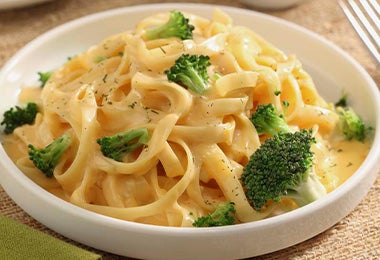 Plato de receta con tallarines en salsa de queso y brócoli Plato de receta con tallarines en salsa de queso y brócoli