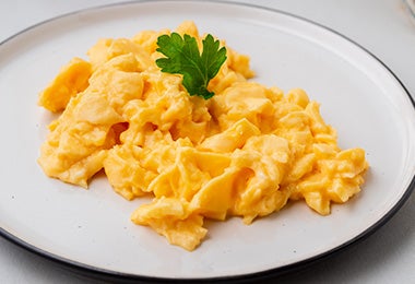 Los huevos revueltos son una forma muy común de hacerlos al desayuno. Huevos revueltos sobre un plato blanco.