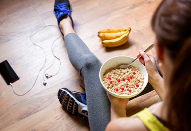 Mujer comiendo avena y banano antes de hacer ejercicio Mujer comiendo avena y banano antes de hacer ejercicio