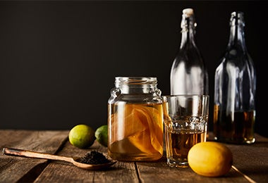 Bebida fermentada de kombucha en una jarra con una cuchara de madera y un par de limones