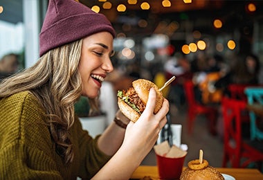 Una chica comiendo una hamburguesa de lentejas para conseguir macronutrientes