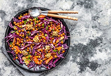 Ensalada de garbanzos tostados con repollo con cuchara y tenedor, un plato con proteínas magras