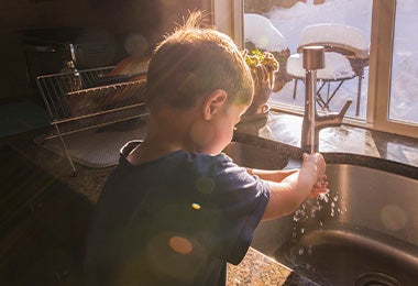 Niño en la cocina enjuagando alimentos para comidas para niños 