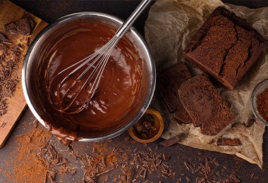 Chocolate derretido en un bowl y un ponqué de chocolate para preparar una Tarta Sacher