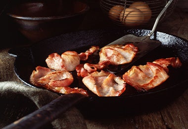 Trozos de tocino cocinados en una sartén 