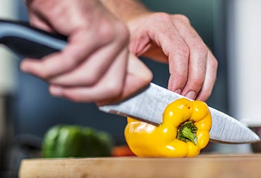 Una persona cortando un morrón con un cuchillo, un utensilio clave para un asado