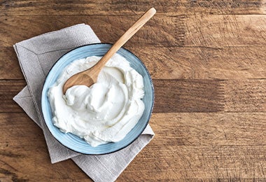Yogur con cuchara de madera, uno de los sustitutos del huevo.