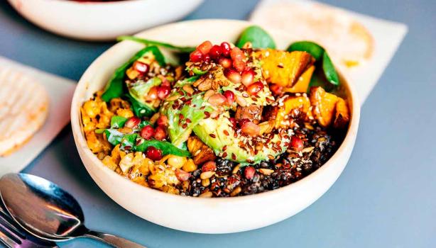 Granos, semillas, frutas y verduras en un plato de comida vegetariana.