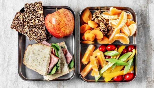 Comida para viaje: barras de cereal, sándwich, frutas, verduras picadas y frutos secos. 