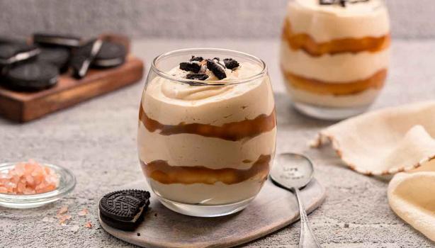 Un postre en vaso con dulce de leche y galletas. 