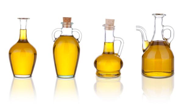 Cuatro jarras con aceite de sésamo en un fondo blanco