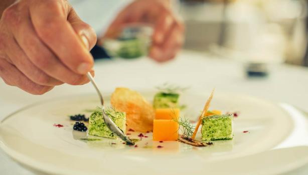 Una persona emplatando con una cuchara una comida con caviar