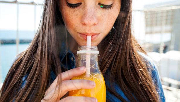 Mujer bebiendo un refrescante jugo de zanahoria con limón.