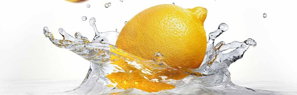 Un tipo de limón amarillo cayendo en el agua. 
