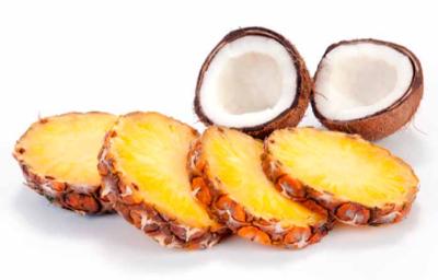 Tajadas de ananá y un coco partido por la mitad, dos frutas tropicales. 