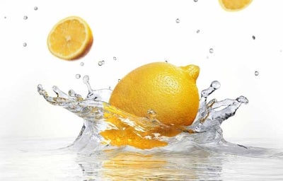 Un tipo de limón amarillo cayendo en el agua. 