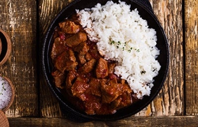 Carne en cuadros y arroz blanco en una sartén de hierro.