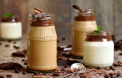 Tres tipos de mousse en vaso con una cuchara y chocolate espolvoreado Tres tipos de mousse en vaso con una cuchara y chocolate espolvoreado