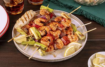 Pinchos con camarones y langostinos al ajillo con verduras y rodajas de limón mandarino