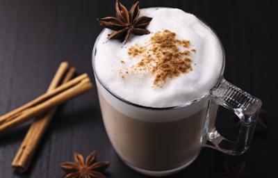 Bebida caliente con leche, canela y anís en una taza de vidrio grueso en una toma en picado Bebida caliente con leche, canela y anís en una taza de vidrio grueso en una toma en picado