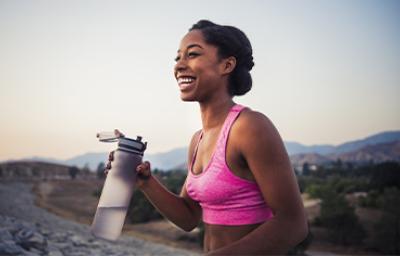 Mujer haciendo deporte e hidratándose con botella reutilizable