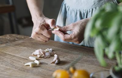Mujer pelando ajos con cuchillo, qué hacer al cortarse en la cocina