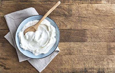 Un plato con yogurt casero recién preparado y una cucharita de madera Un plato con yogurt casero recién preparado y una cucharita de madera