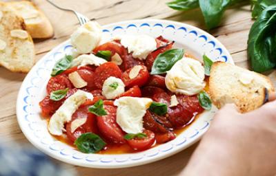 Ensalada caprese con tomate, queso, albahaca y pan en un plato Ensalada caprese con tomate, queso, albahaca y pan en un plato