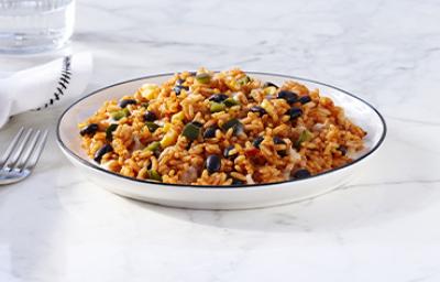 Toma lejana de arroz negro con cubiertos y un vaso de agua Toma lejana de arroz negro con cubiertos y un vaso de agua