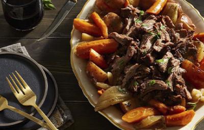 Carne de cabrito asado sobre cama de vegetales y papas