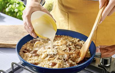 Una persona preparando una receta de cocción lenta con champiñones, crema y arroz Una persona preparando una receta de cocción lenta con champiñones, crema y arroz