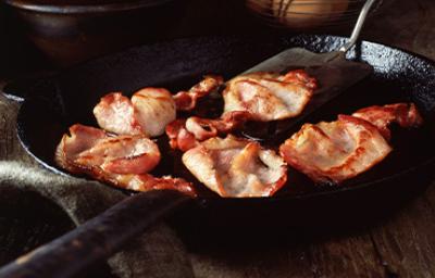Deliciosa panceta cortada siendo fritada en un sartén