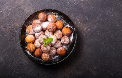 Plato de buñuelos de mandioca espolvoreados vistos desde un ángulo cenital.