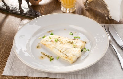 Plato con filete de merluza, salsa y hierbas 