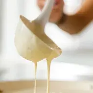 Una mujer preparando pancakes con un cucharón 