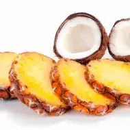 Tajadas de ananá y un coco partido por la mitad, dos frutas tropicales. 