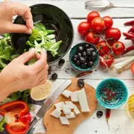 Una persona preparando una ensalada navideña, deliciosa y colorida. 
