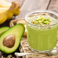 Palta partida a la mitad con un batido de cereal y verduras para desintoxicar el cuerpo