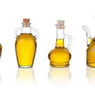 Cuatro jarras con aceite de sésamo en un fondo blanco
