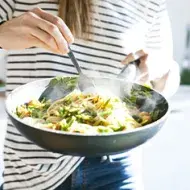 Una persona cocinando su comida con menos de 5 ingredientes en una sartén