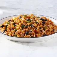 Toma lejana de arroz negro con cubiertos y un vaso de agua