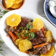 Plato de cerdo con salsa de naranja, acompañado de rodajas de naranja