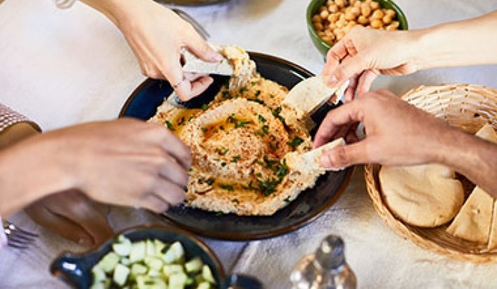 Hummus servido en una mesa con amigos, una comida vegana deliciosa. Hummus servido en una mesa con amigos, una comida vegana deliciosa.